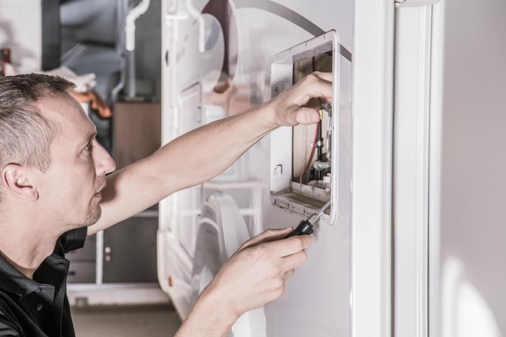 A Man Is Fixing A Caravan With A Screwdriver — Cairns Caravan Repairs In Edmonton, QLD