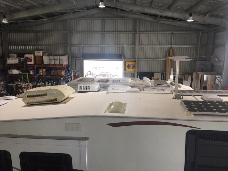 A White Rv Is Sitting In A Warehouse With A Roof Fan On Top Of It — Cairns Caravan Repairs In Edmonton, QLD