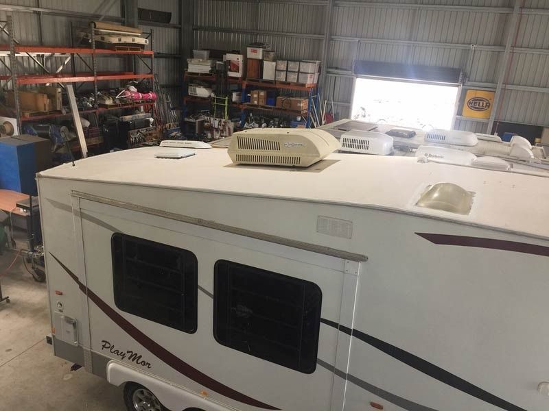 A White Rv Is Parked In A Garage — Cairns Caravan Repairs In Edmonton, QLD