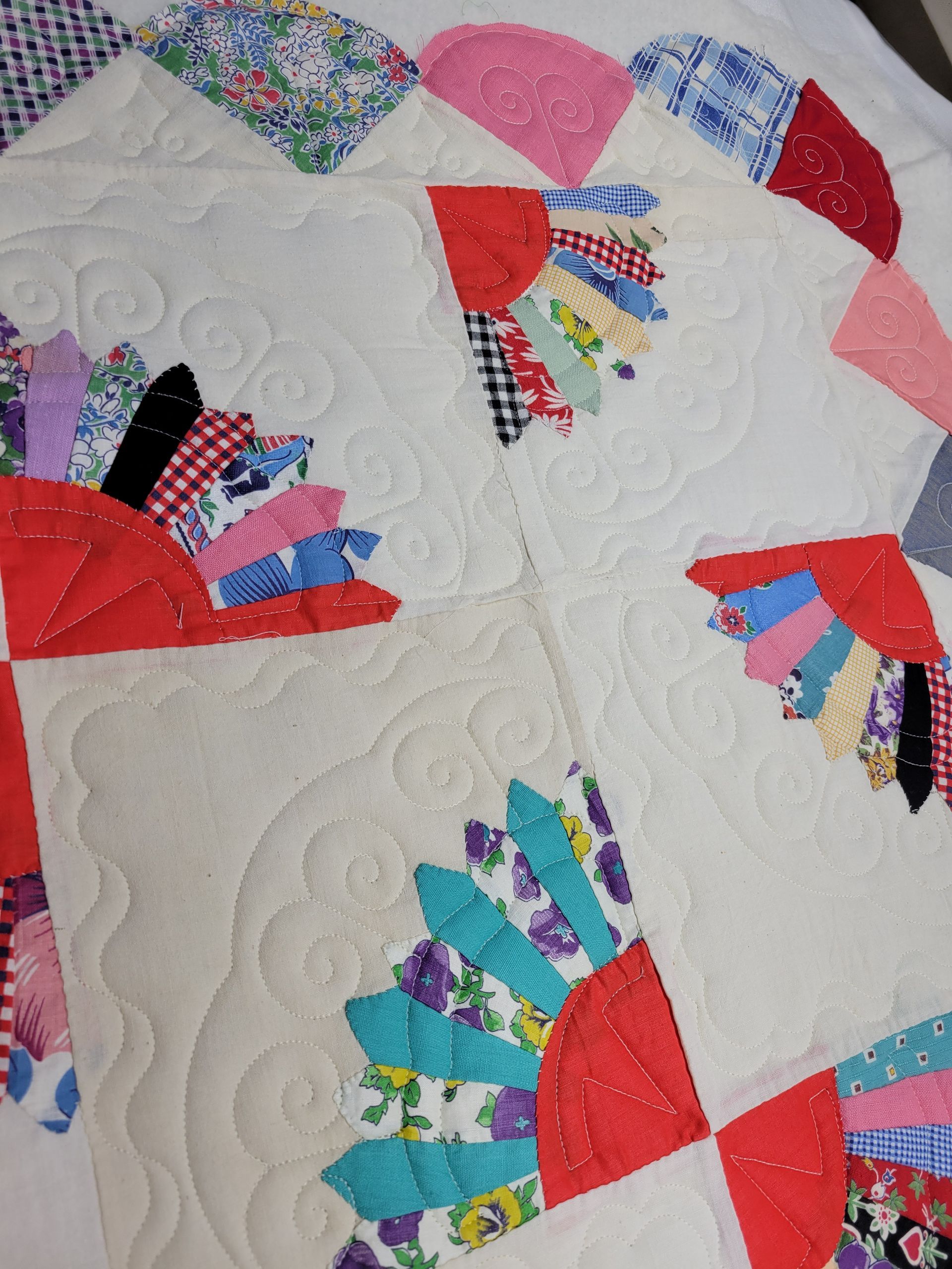 Colorful fan-shaped quilt blocks on a white, textured background