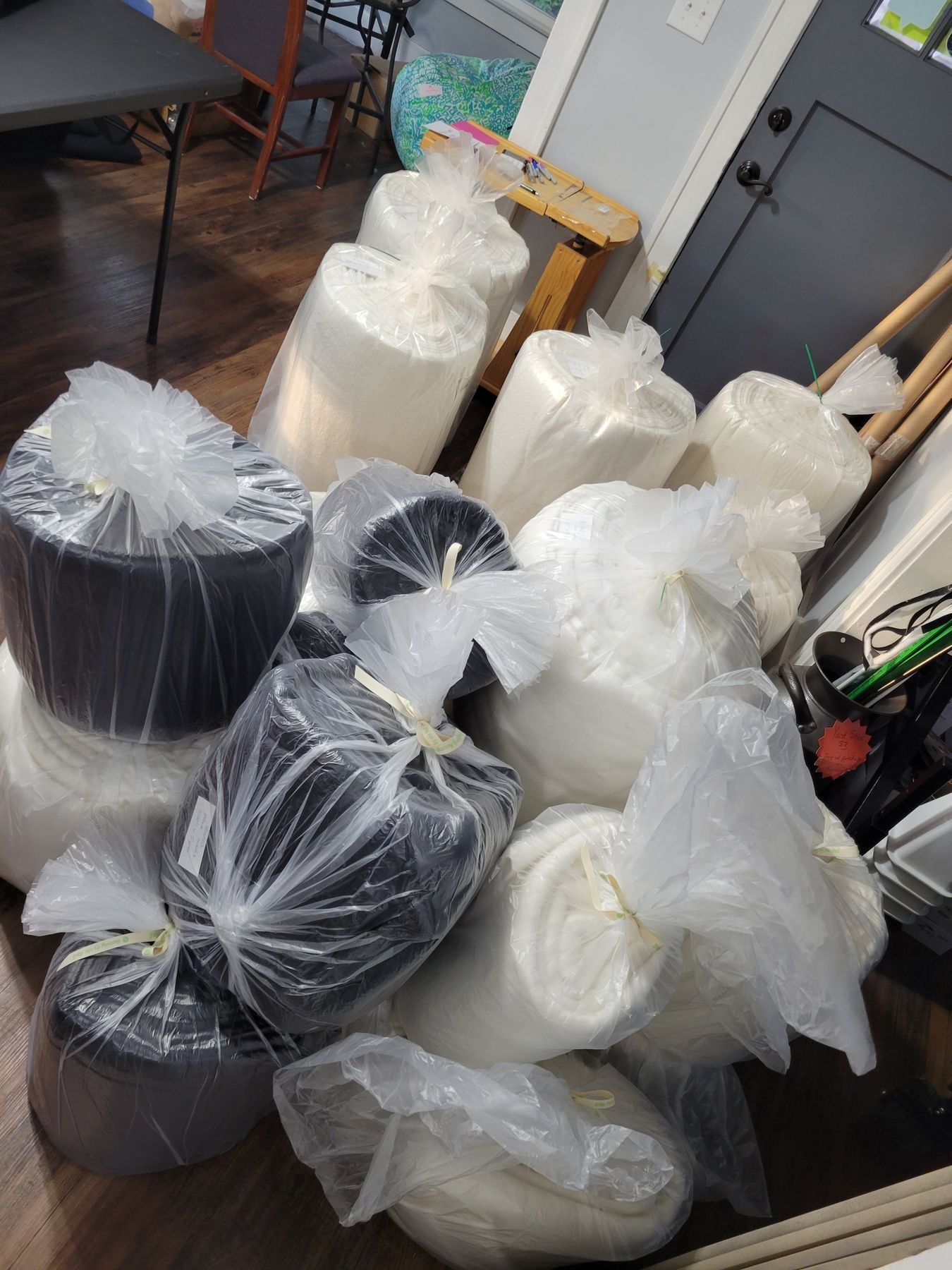 Plastic-wrapped rolls of black and white material stacked on a table in a workshop