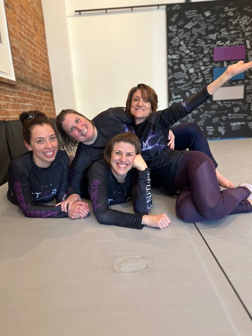 People practicing hand techniques in a martial arts studio with mats and brick walls