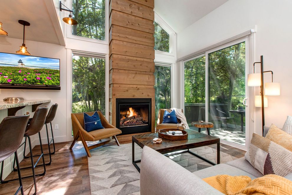 Bright modern living room with fireplace, large windows, sectional sofa, and bar seating