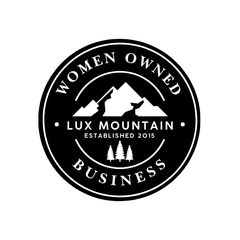 Black circular logo reading “Women Owned Business” with mountain graphic and “Lux Mountain” in the center.