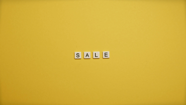 Small white letter tiles spelling “SALE” on a yellow background.