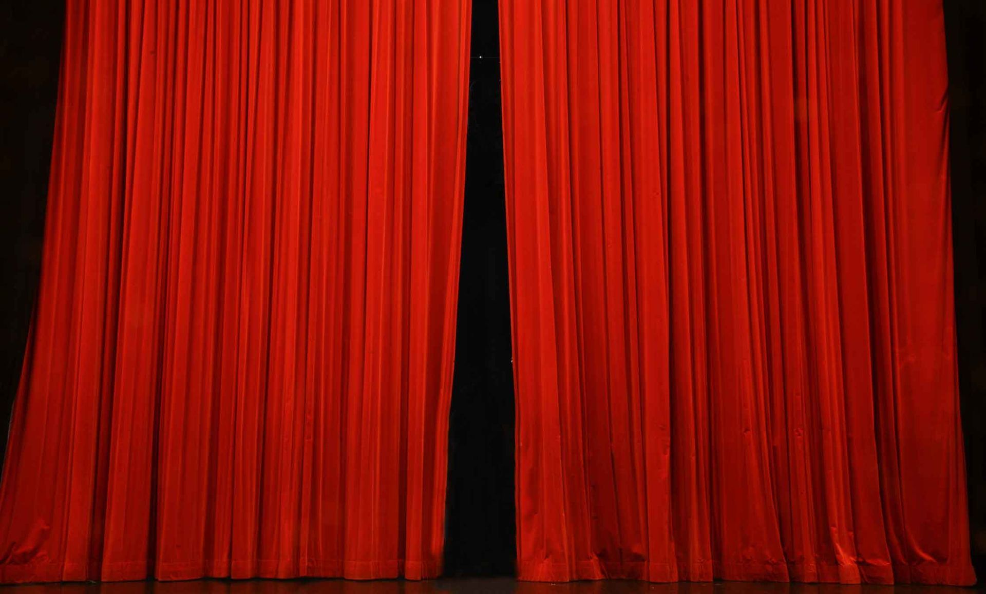 A pair of red curtains are open on a stage.