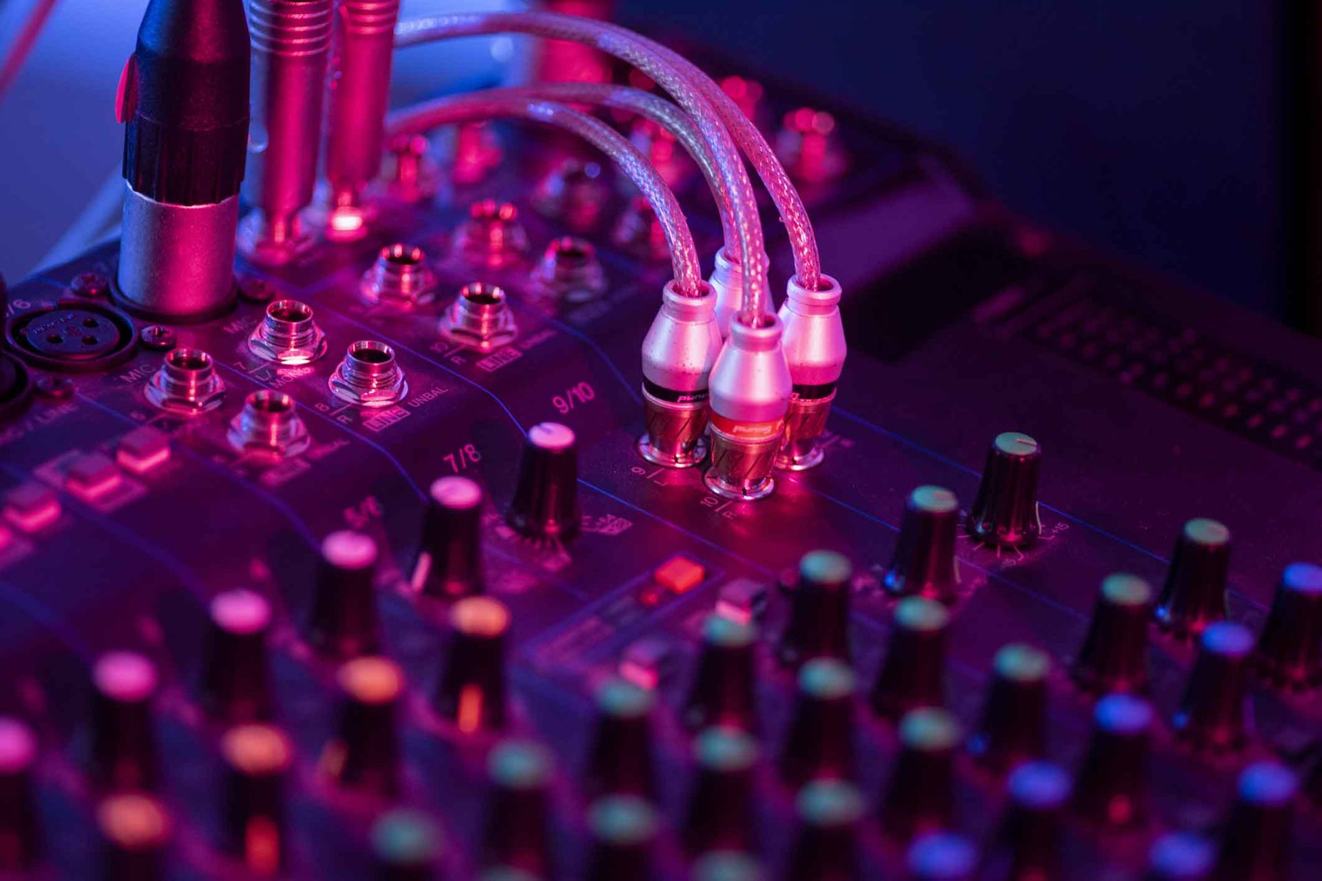 A close up of a sound mixer with purple lights on it.