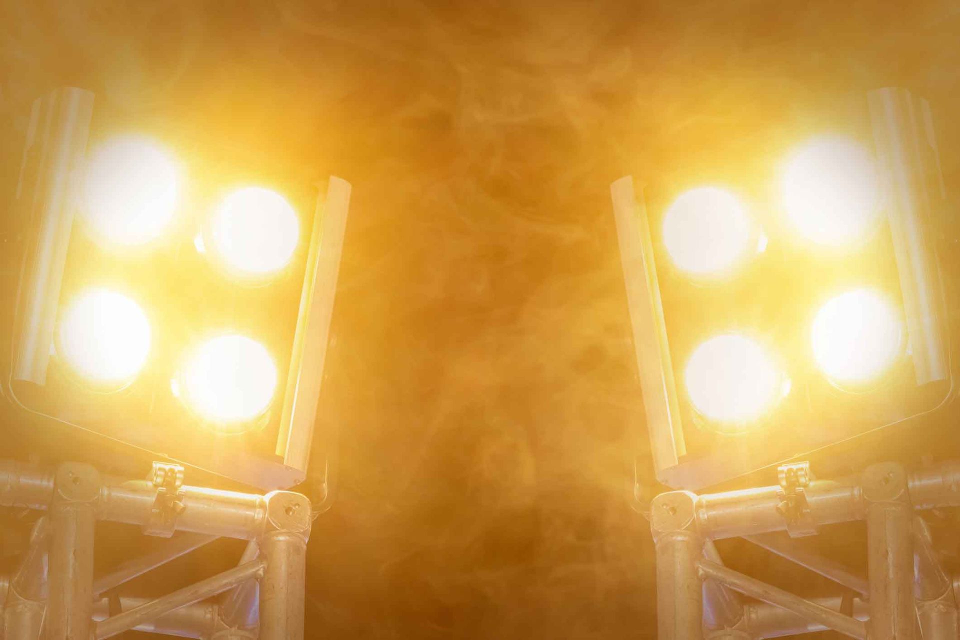 Two spotlights are shining in the dark with smoke coming out of them.