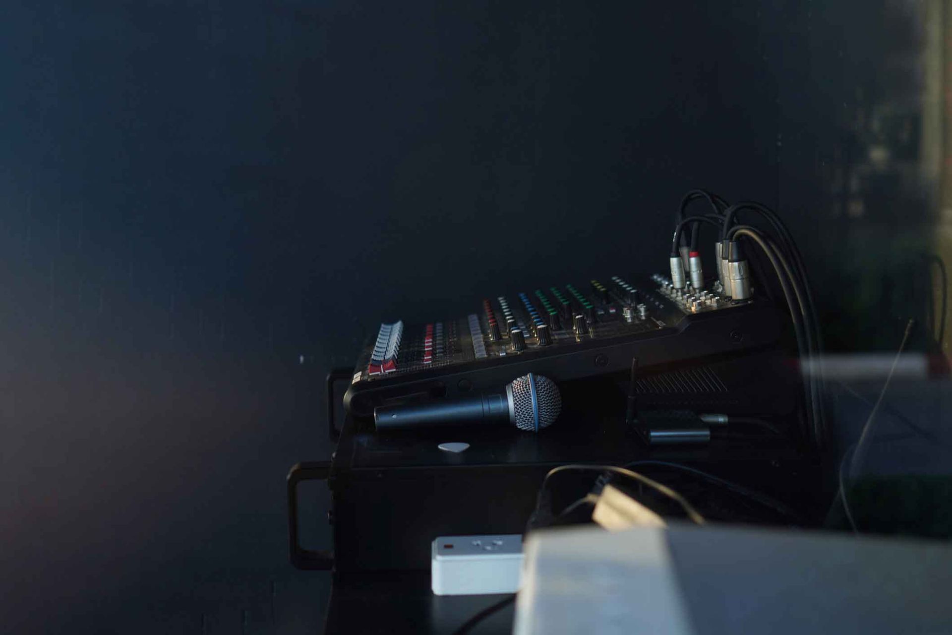 A microphone is sitting on top of a mixer on a table.