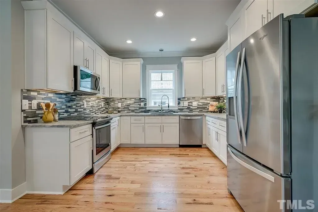 Bright modern kitchen with white cabinets, stainless steel appliances, and hardwood floors