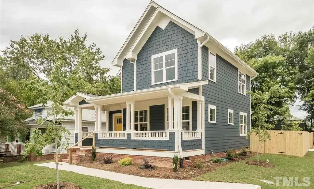 Blue two-story house with white trim and a front porch on a landscaped corner lot