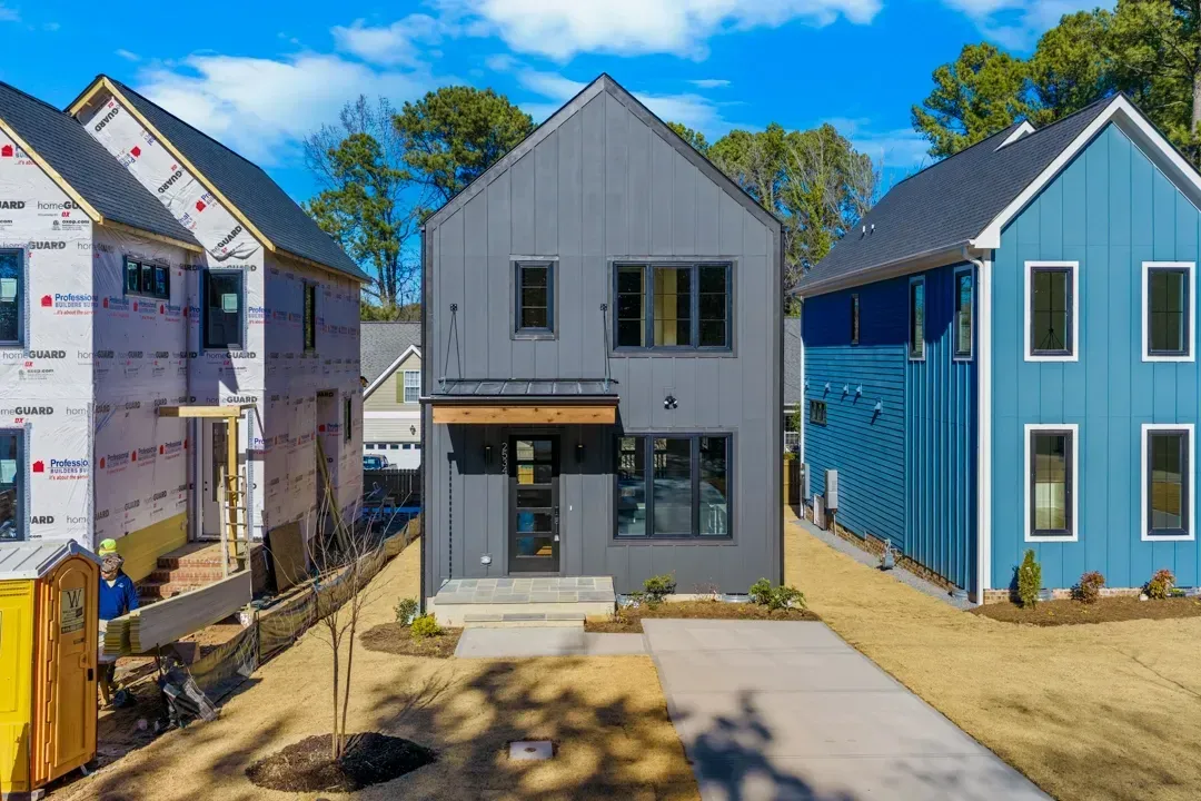 Row of newly built houses, with a gray home centered between a white and blue house.