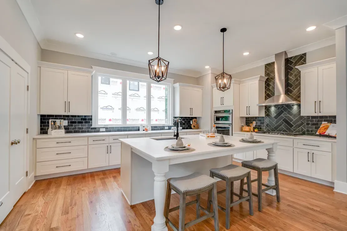 Bright white kitchen with island, pendant lights, stainless appliances, and hardwood floors
