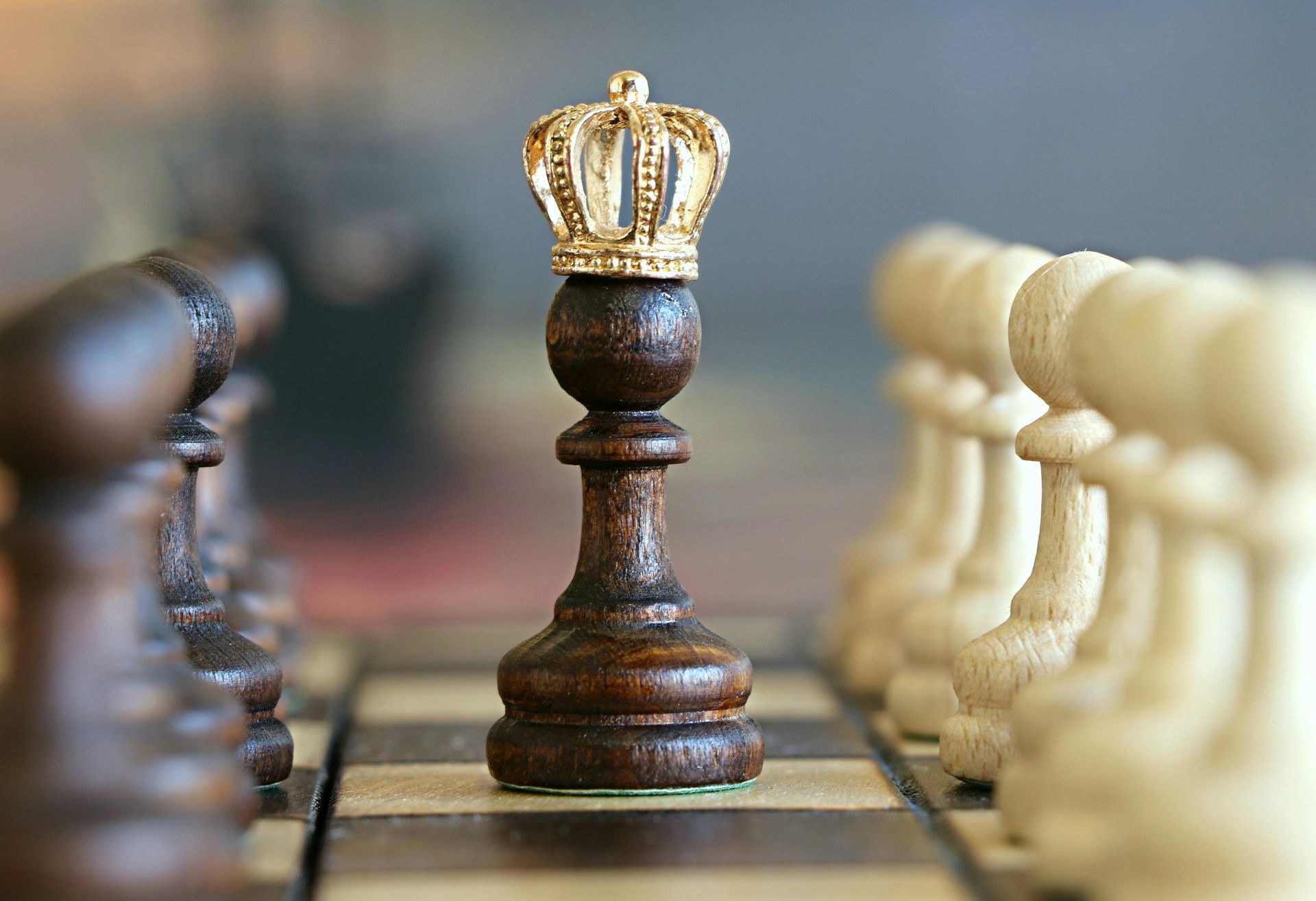 A wooden chess piece with a crown on top of it on a chess board.