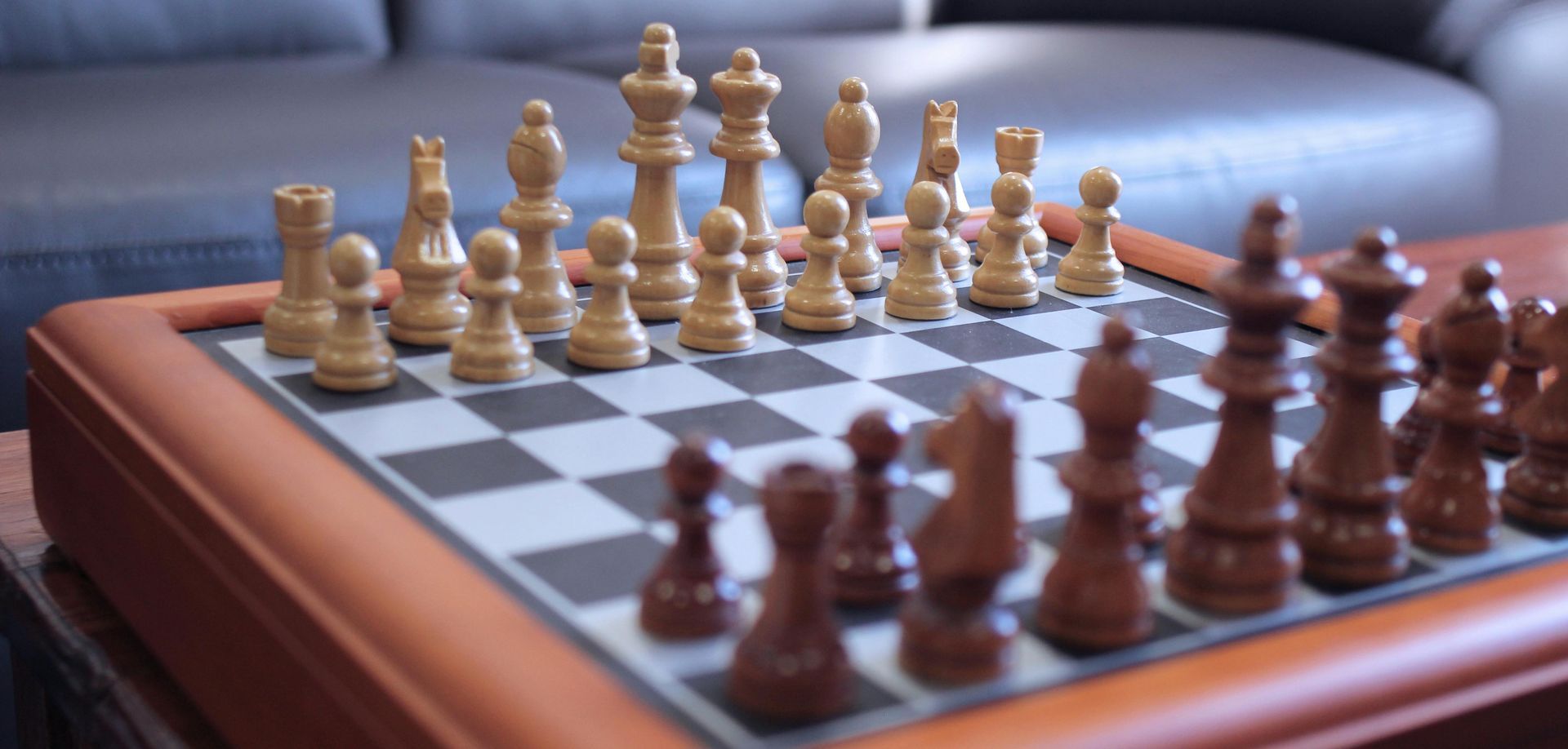 A wooden chess board with chess pieces on it in a living room.