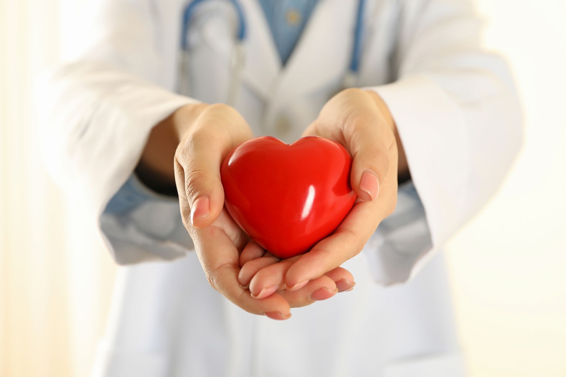 Medical professional holding a red glass ornament shaped as a heart.