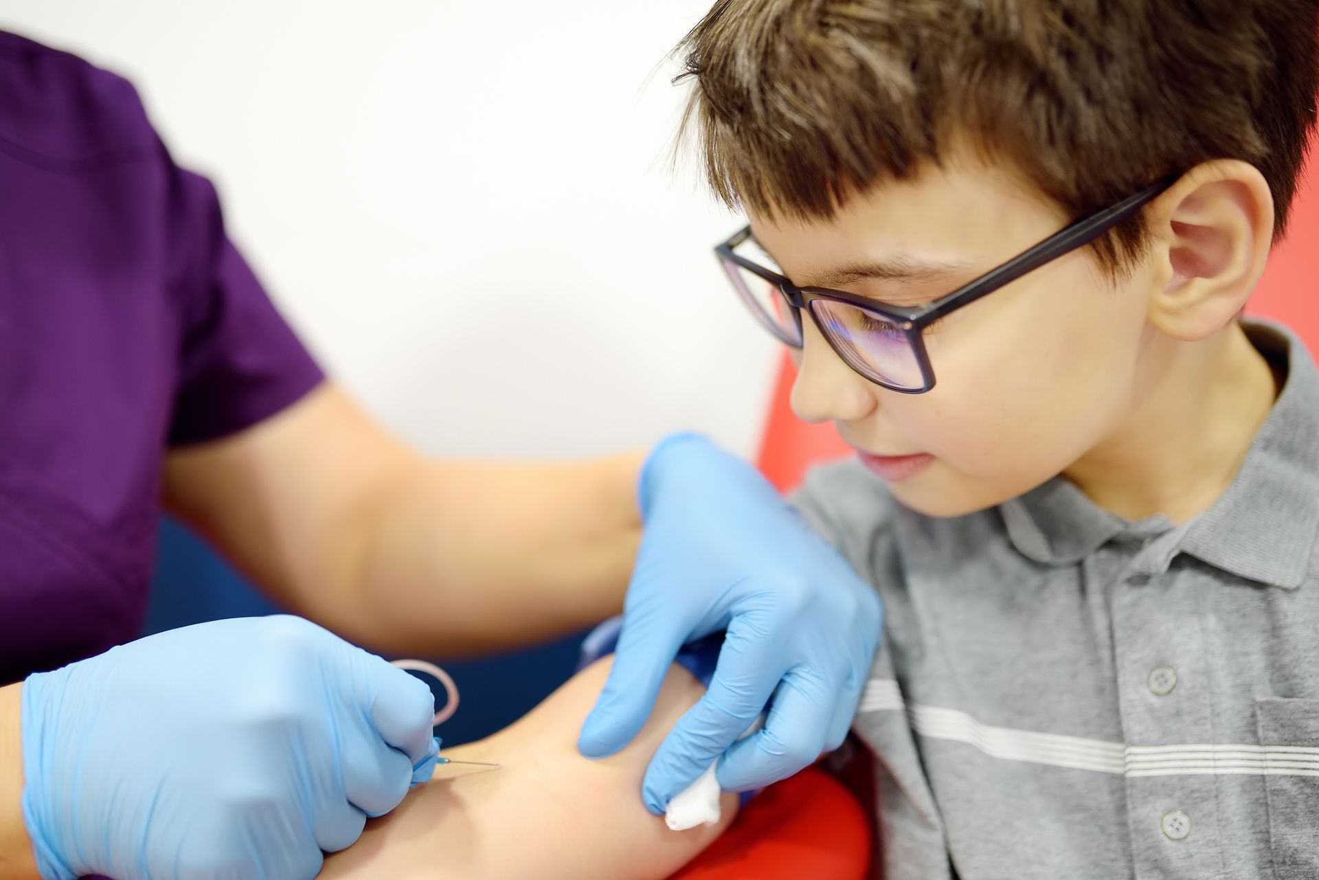A healthcare worker drawing blood from a young boy's arm.