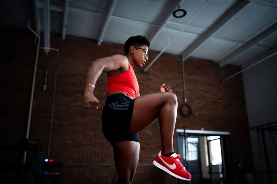 Person in red sportswear doing a high-knee exercise in a gym or studio