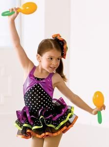 Young girl in a purple polka-dot dress dancing with orange maracas against a white background