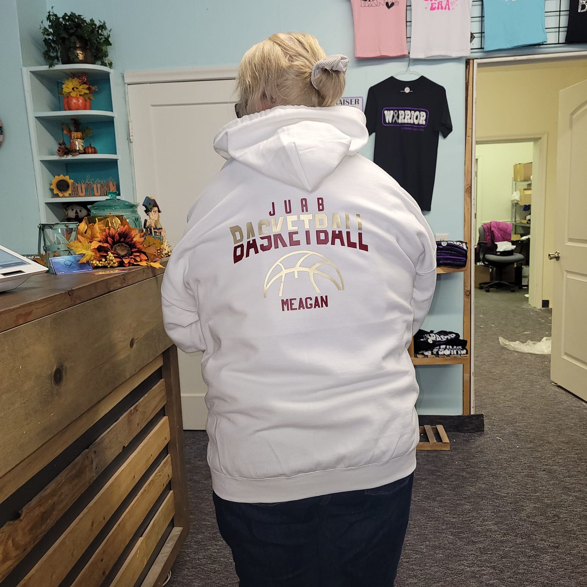 A woman wearing a white hoodie that says basketball on it