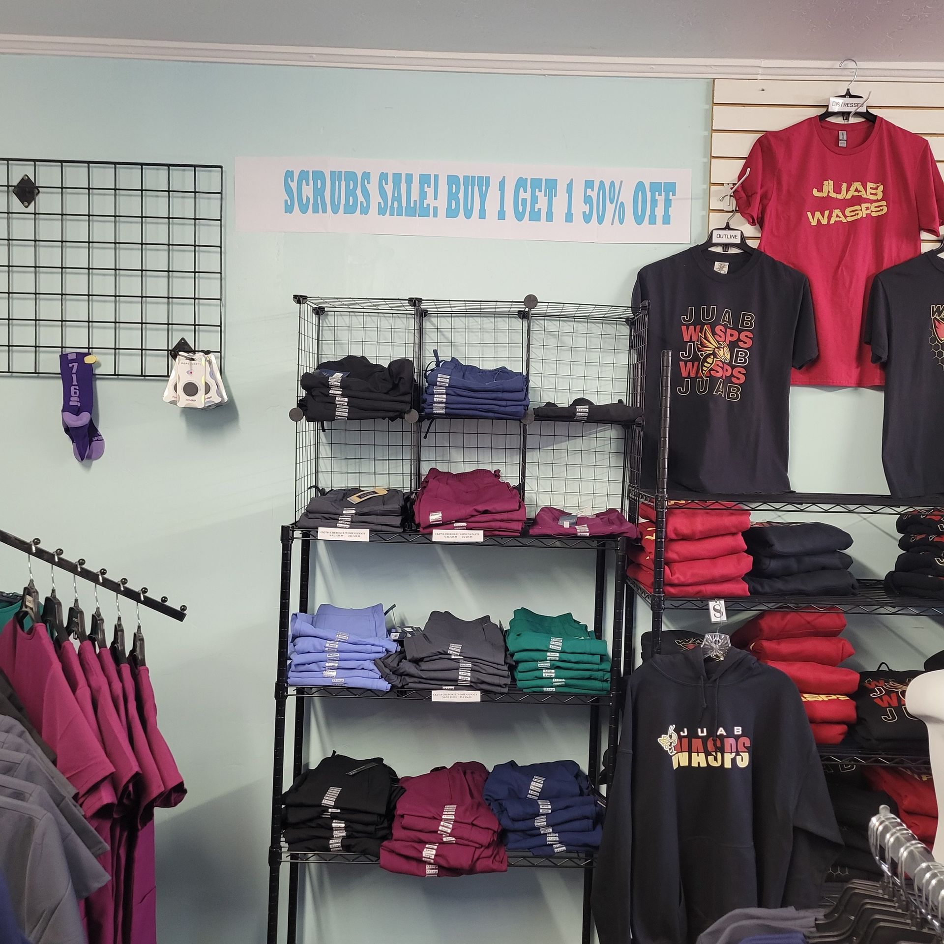A store with a sign that says scrubs sale buy get 50 % off