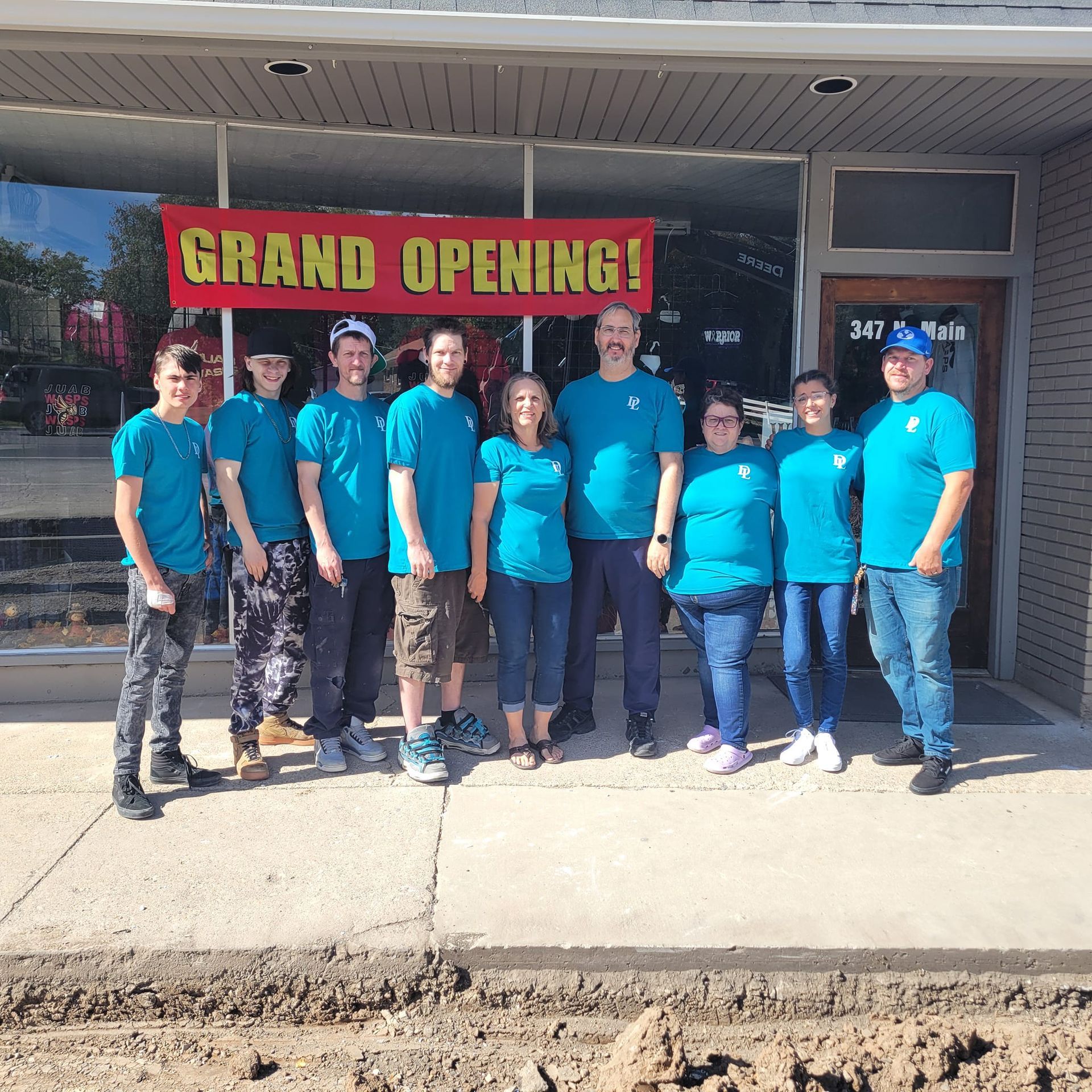 A group of people standing in front of a store with a sign that says grand opening