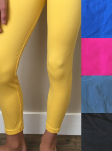Person wearing bright yellow leggings, shown from waist to ankles against a white wall with color swatches.