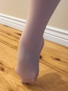 Foot pressing onto a wooden floor near a white baseboard.