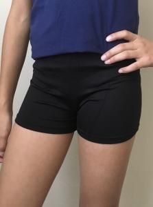 Person wearing a blue top and black shorts standing indoors
