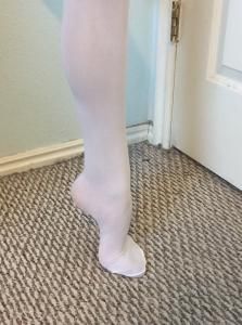 Bare foot and lower leg standing on carpet beside a white door