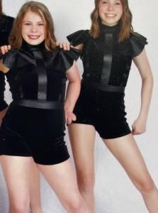 Two women in black outfits posing against a light background