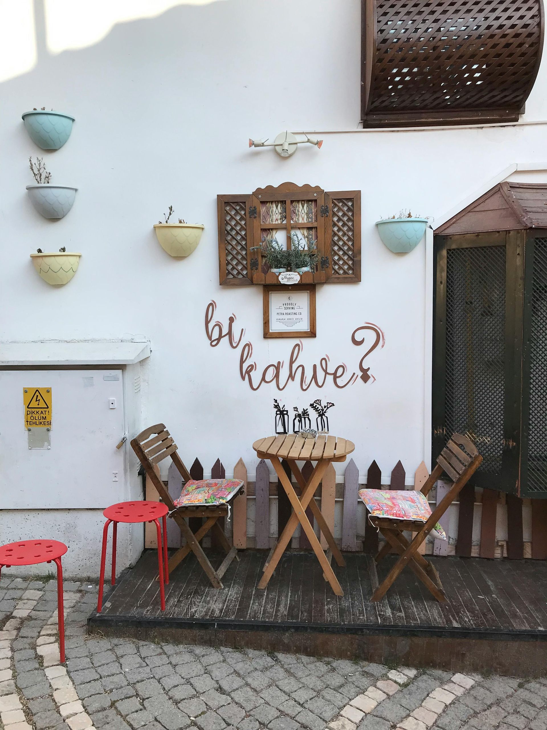 A table and chairs in front of a wall that says bikahve