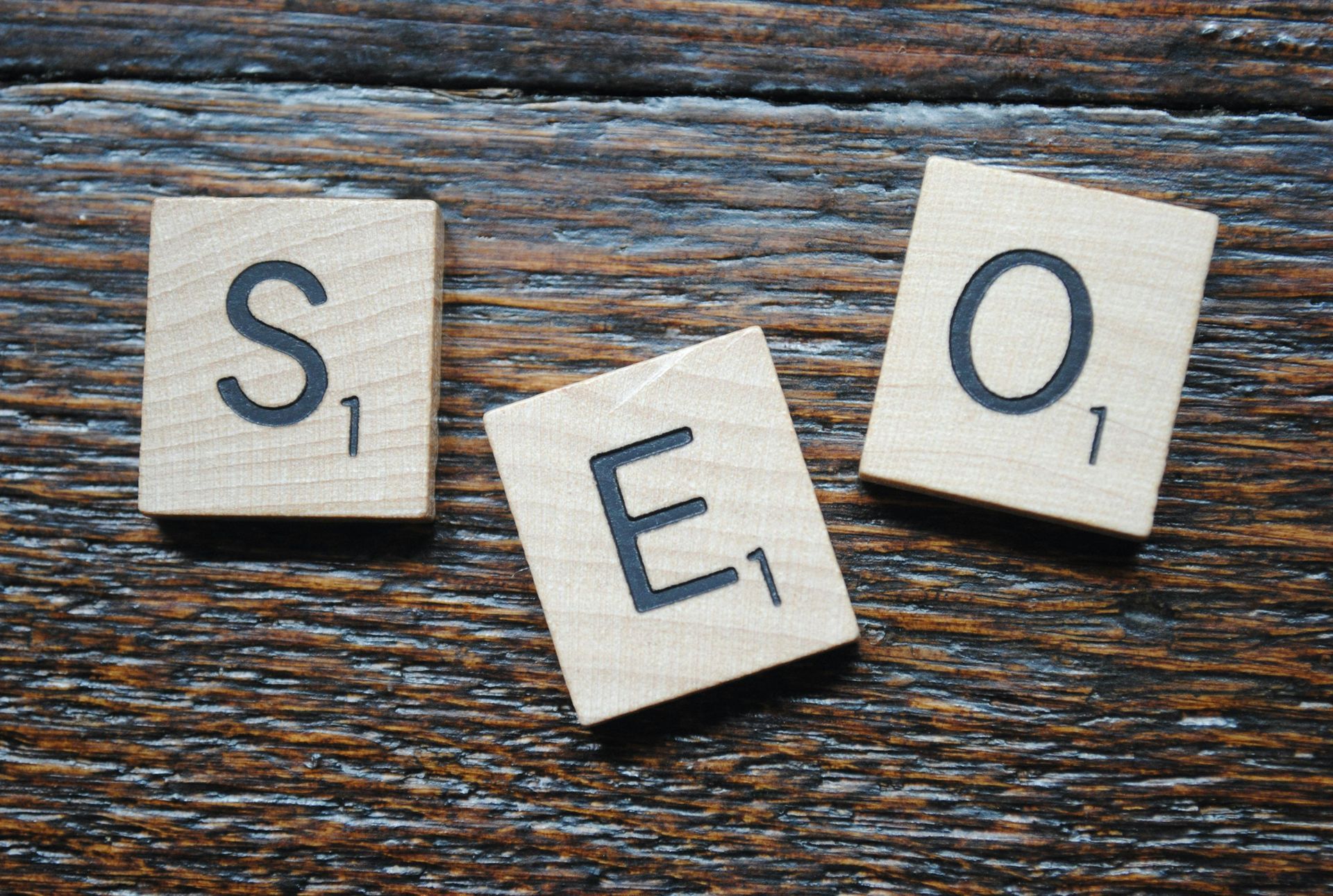 The word seo is written on scrabble tiles on a wooden table.