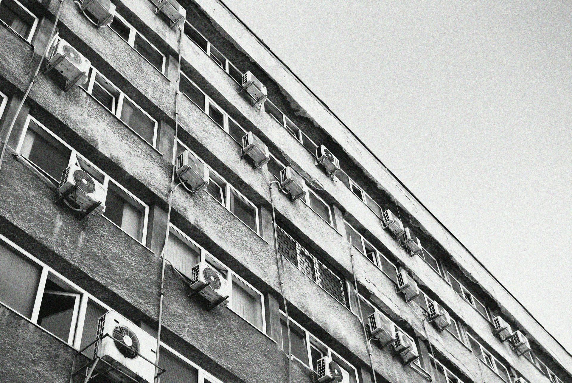 A black and white photo of a building with air conditioners on the side