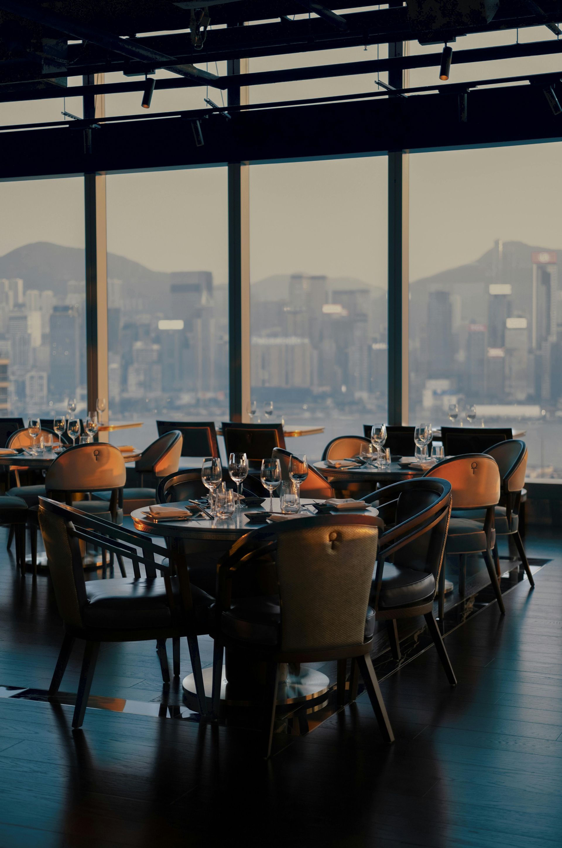 A restaurant with tables and chairs and a view of the city.