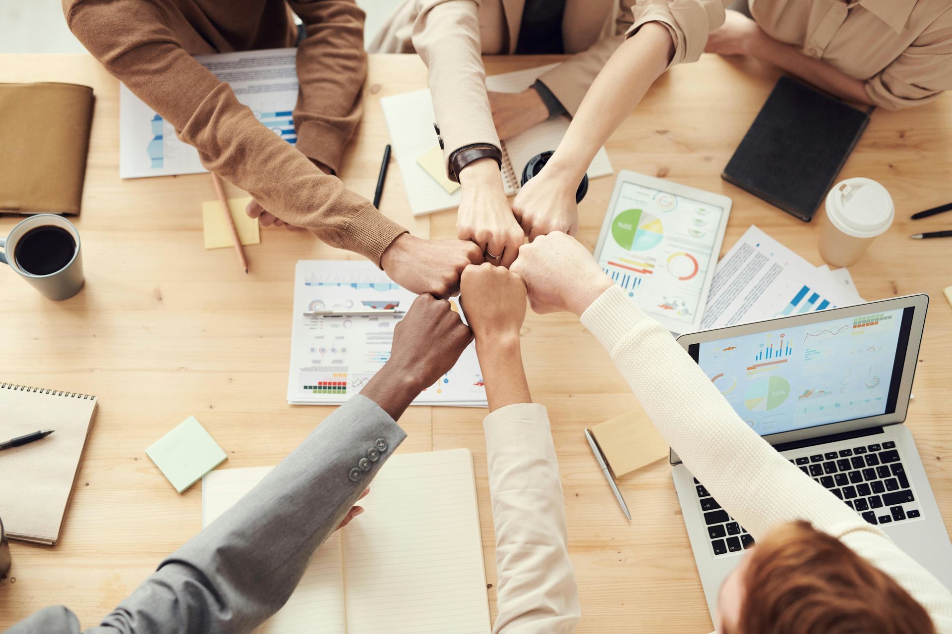 A group of people are putting their hands together in a circle.