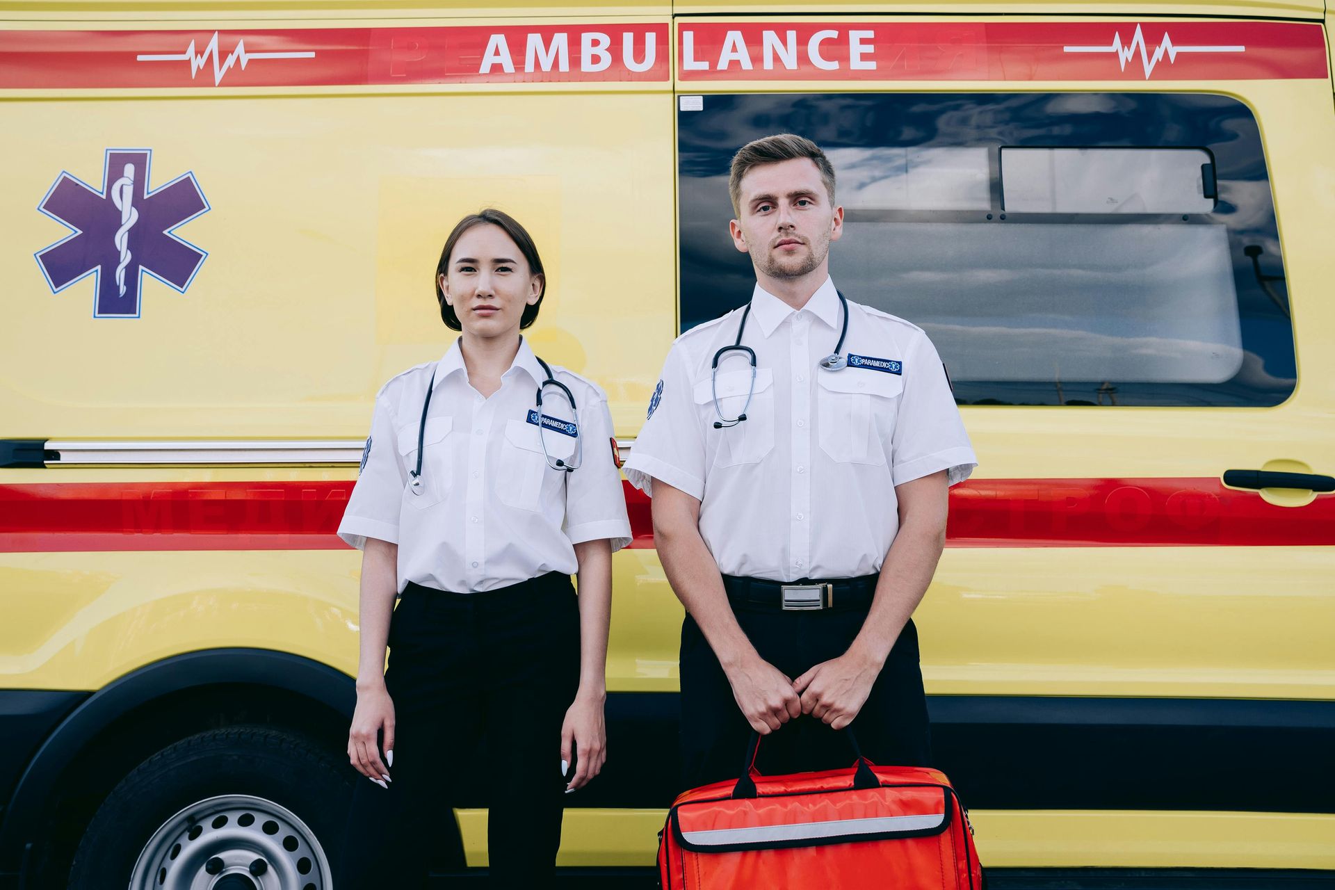 A man and a woman are standing in front of an ambulance.