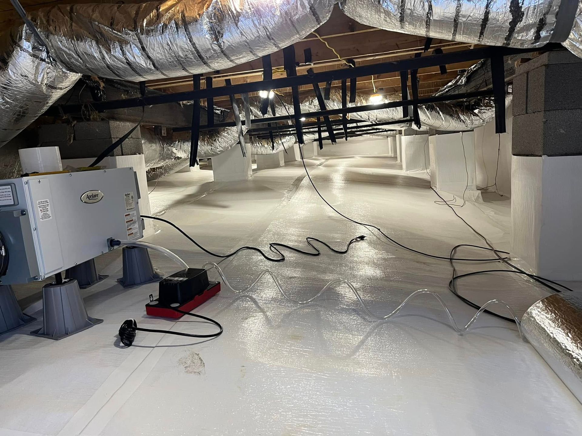 Crawlspace with white flooring, insulation, and mechanical equipment.