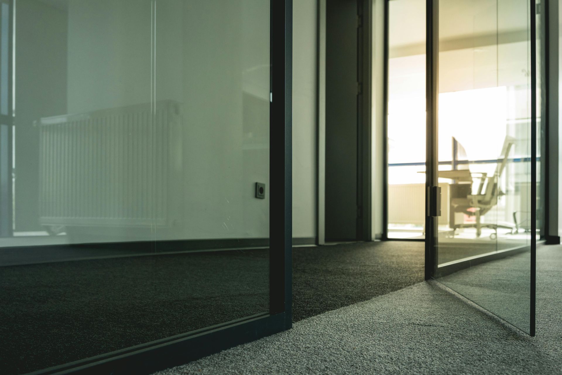 Glass-walled office with dark trim. A sunny interior space is visible.