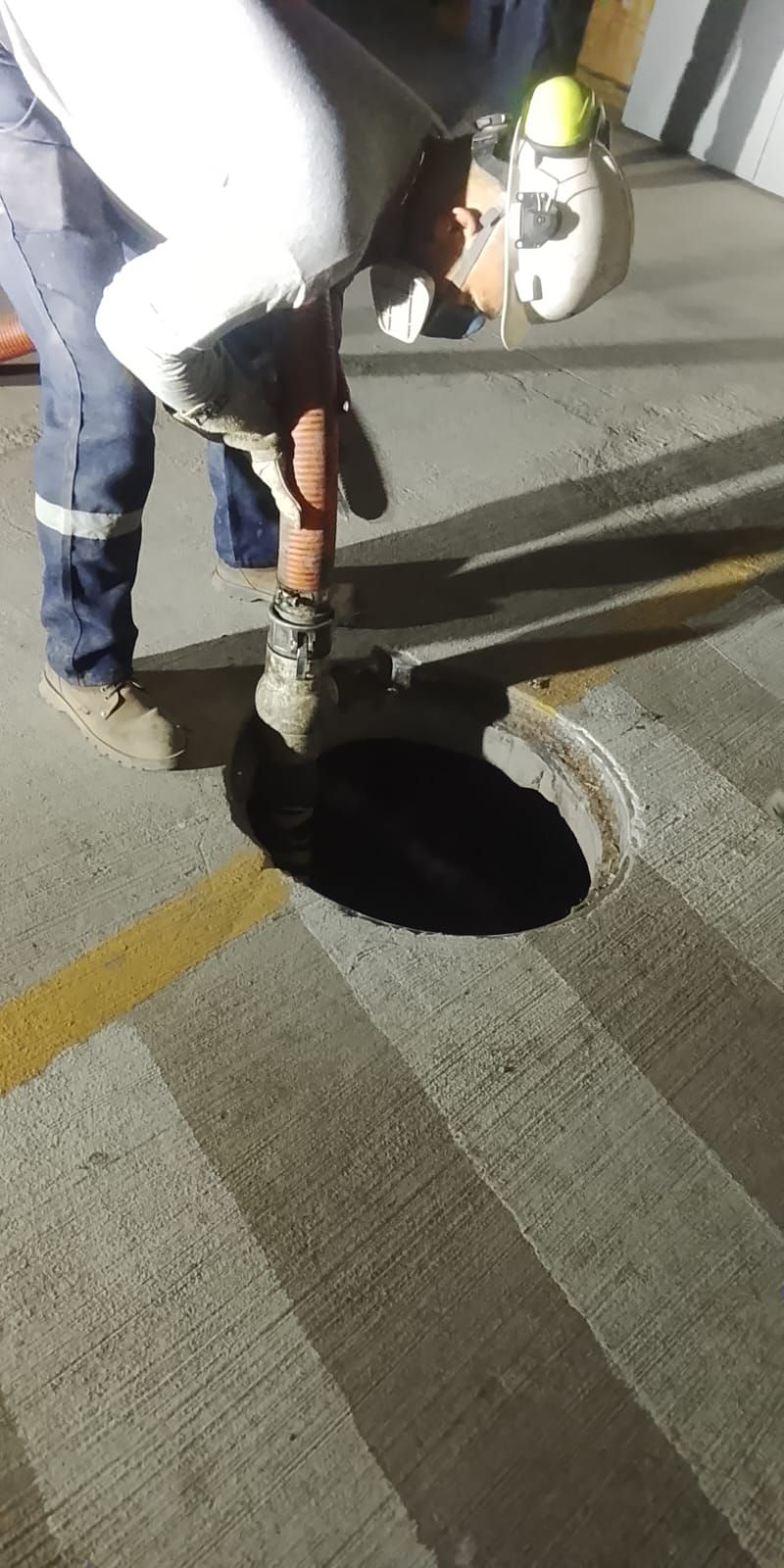 Trabajador vierte líquido oscuro en un agujero circular sobre una superficie