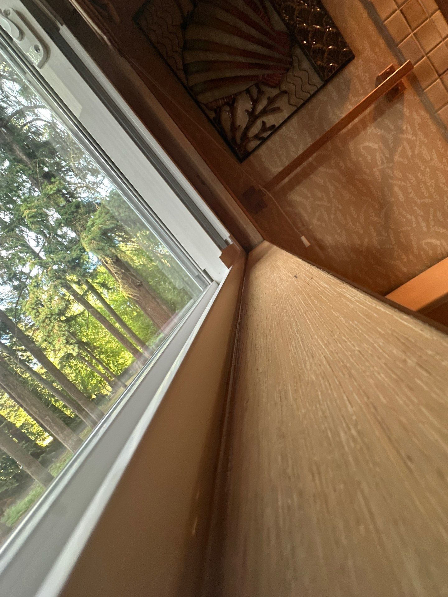 Wooden indoor hallway with a large window overlooking trees and a decorative wall hanging