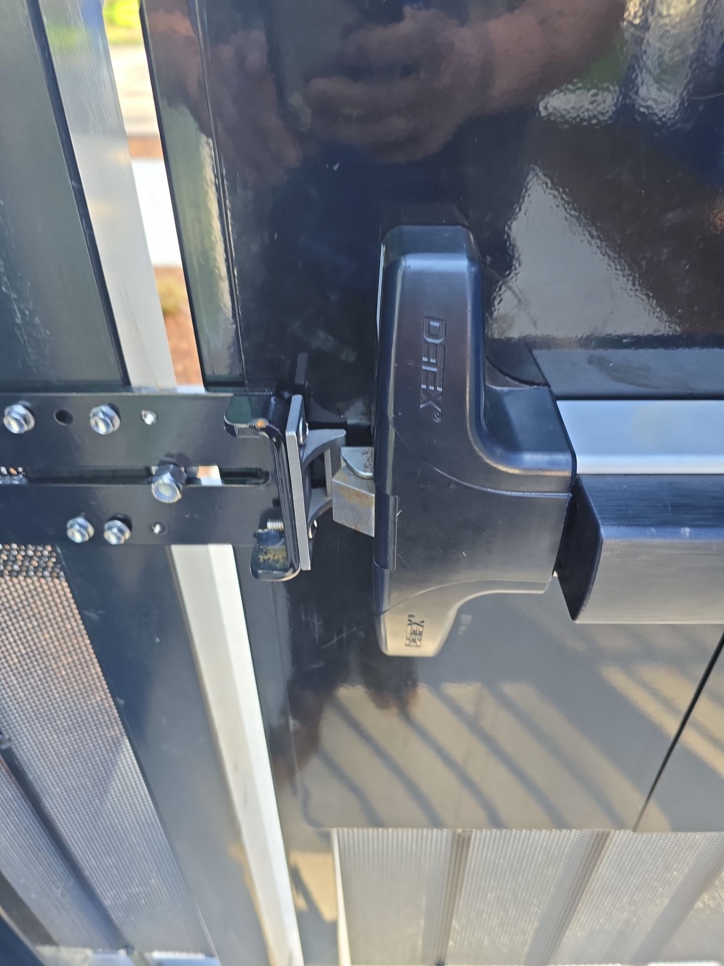 Close-up of a black metal gate latch and handle on a textured outdoor door.