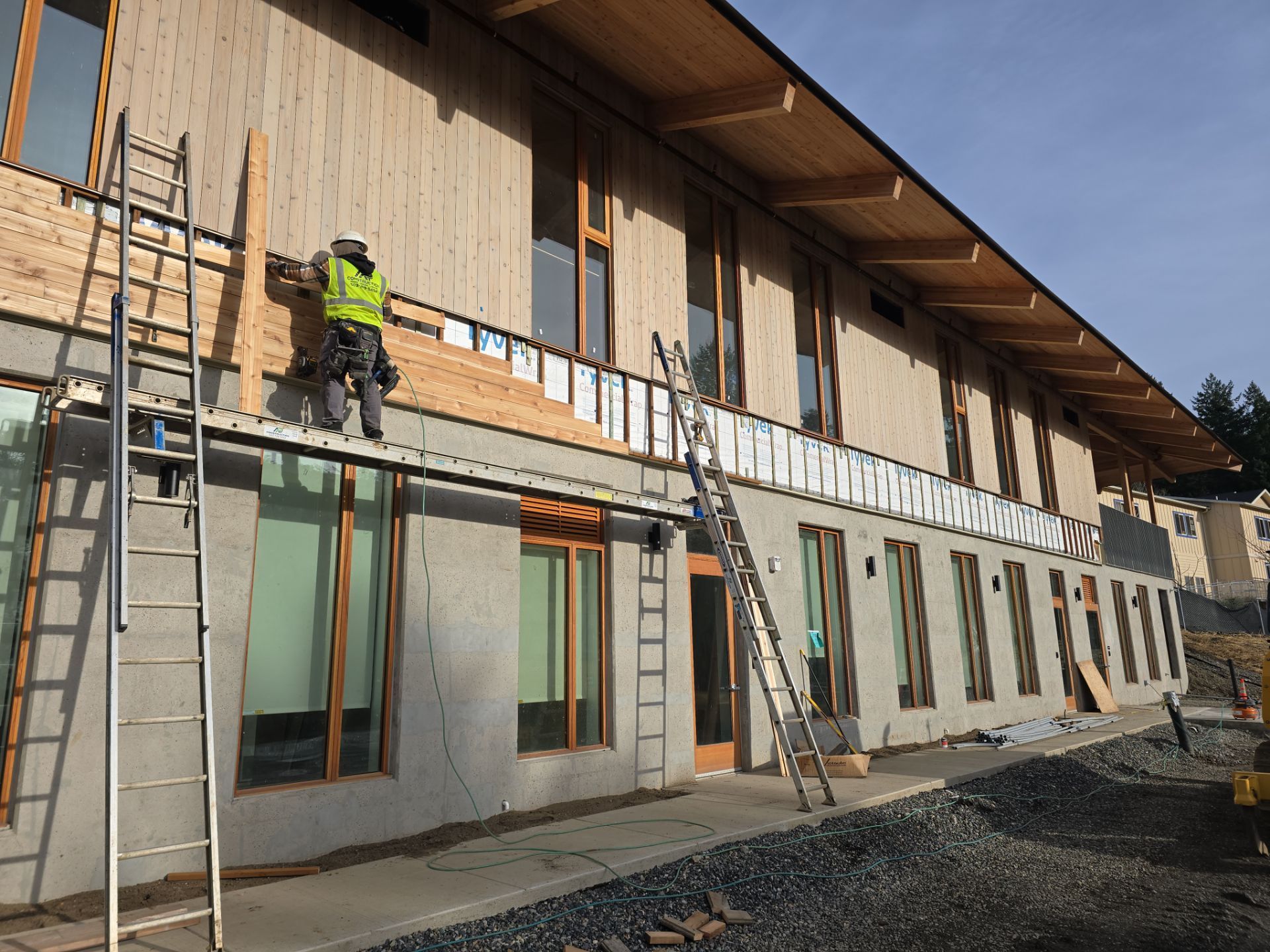 Workers on scaffolding installing siding on a two-story building exterior