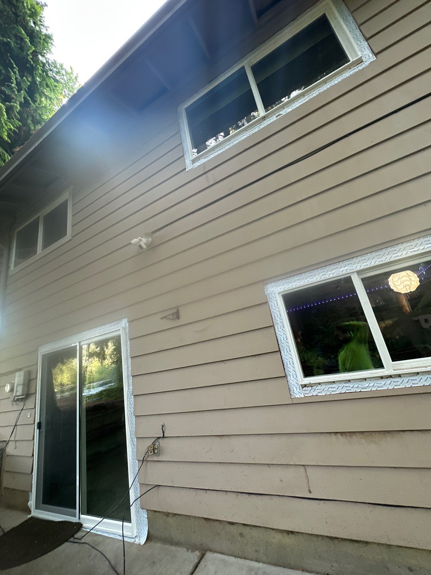 Exterior of beige house with sliding glass door and windows, viewed from a low angle