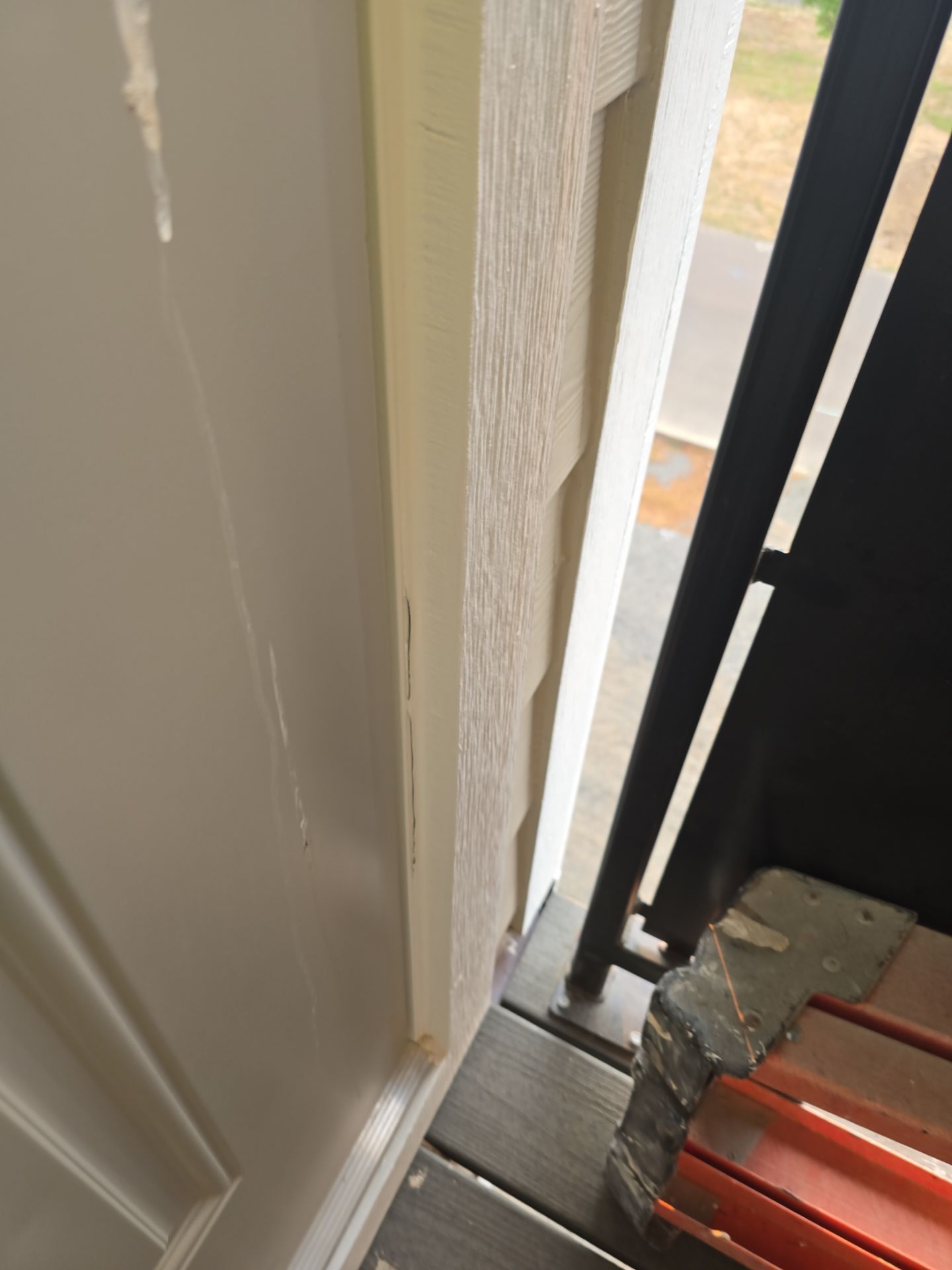 Narrow doorway with white trim, black railing, and an orange step or object at the bottom edge.