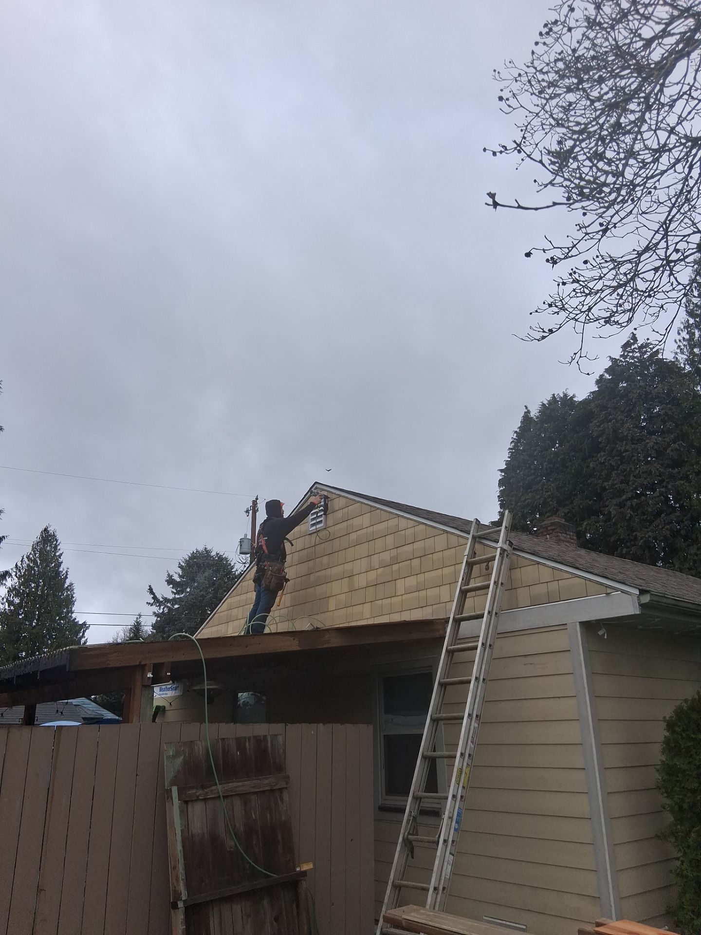 Roof repair with ladder beside a house under a cloudy sky