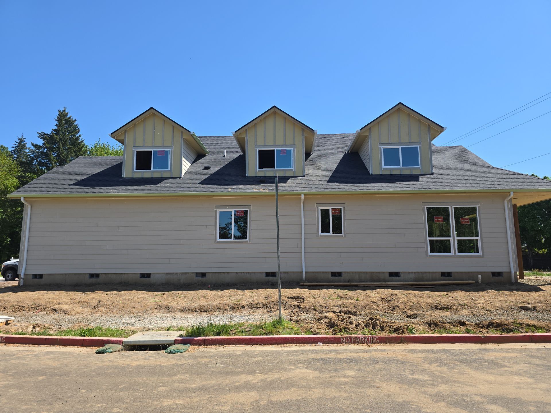 Single-story beige house with three dormer windows and a small front window under a blue sky.