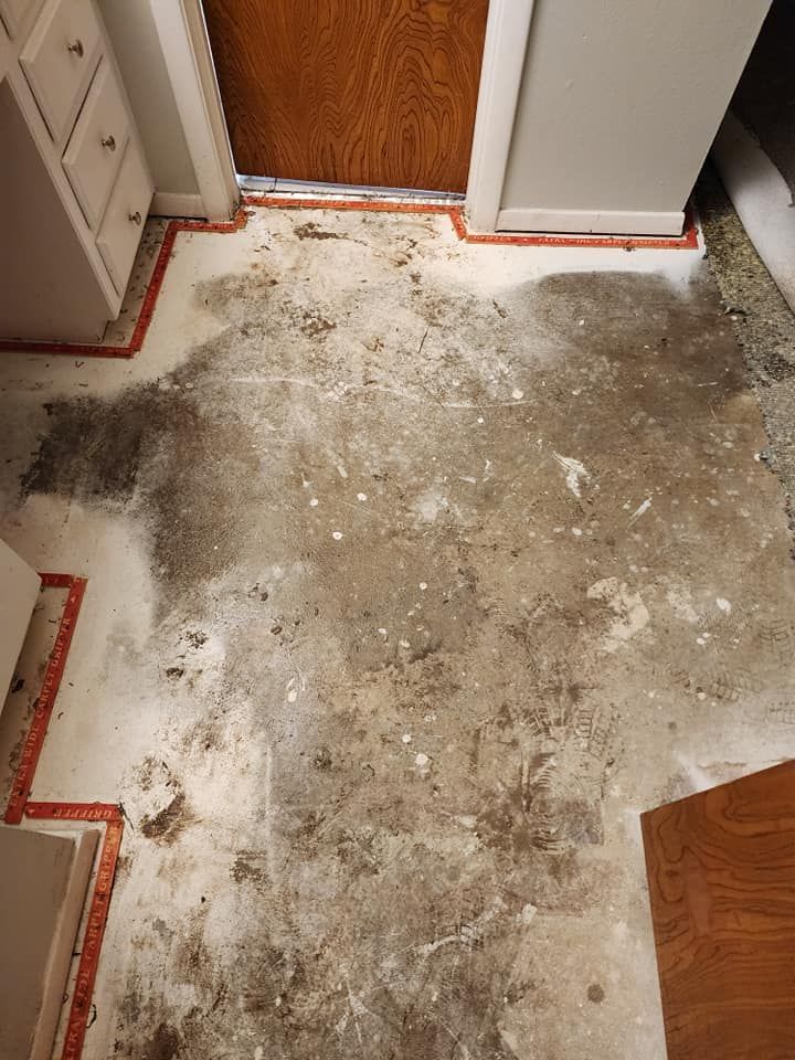 Bare floor with dirt and debris near a doorway and cabinets, red trim.