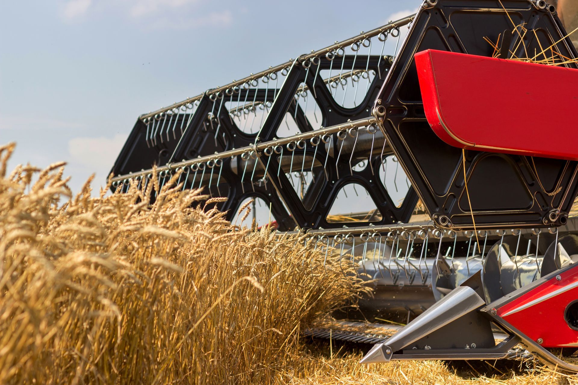 Combine harvester cutting wheat in a field; red and black machinery.