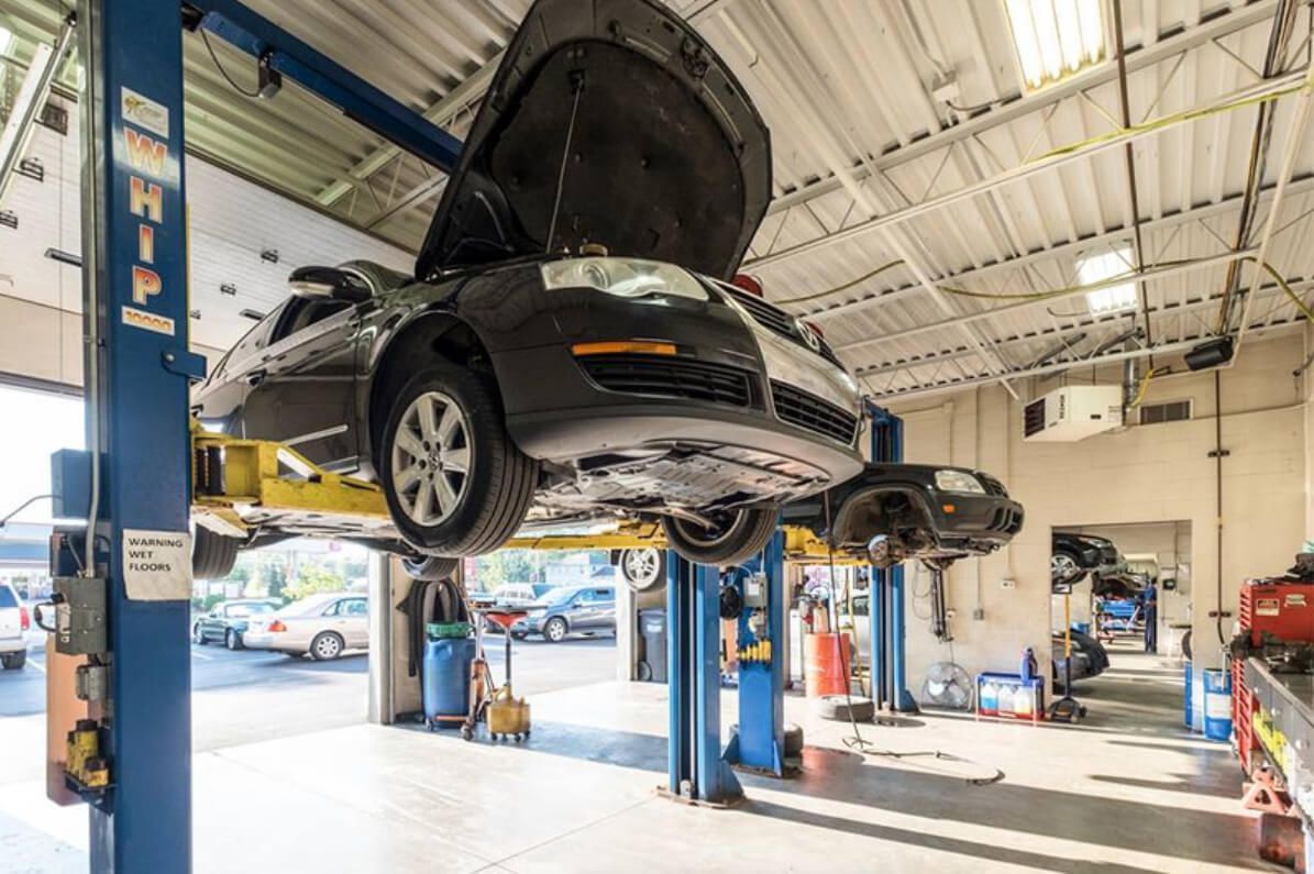 Car being repaired on a lift in an auto repair shop; another car visible in background. | Arie Nol Auto Center